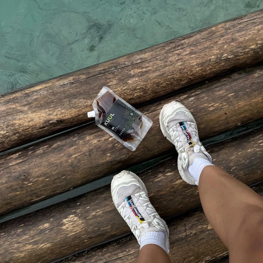 Pouch KUUL sobre troncos junto al agua — aventura en la ruta